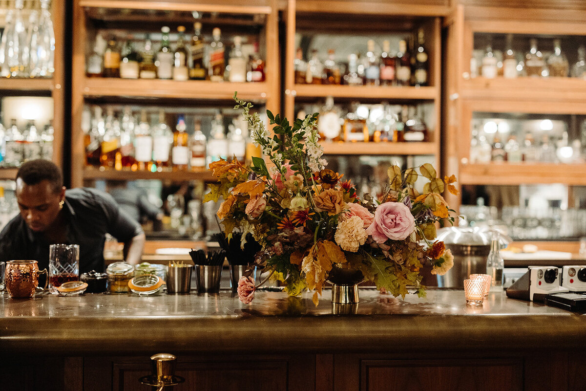 Tasteful cocktail hour florals create an inviting space in hues of dusty rose, burgundy, mauve, taupe, copper, and lavender. Florals composed of roses, clematis, lisianthus, spray roses, copper beech, and fall foliage. Design by Rosemary and Finch in Nashville, TN.