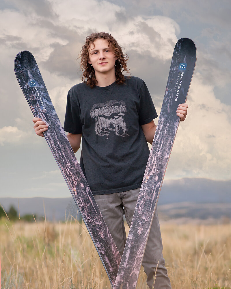 high-school-senior-colorad-with-skis-cool-sky-in-field