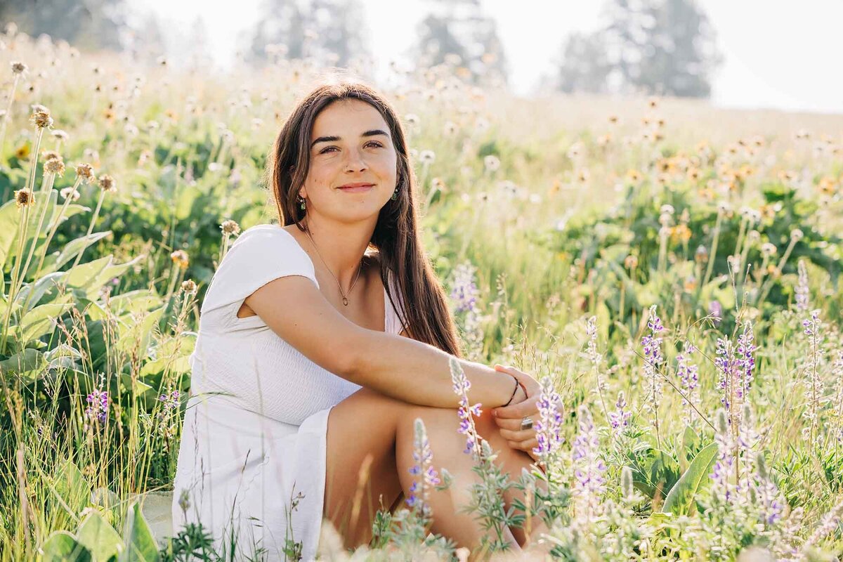 Senior photo Montana high school girl sitting in wildflower field at North Loop Trail, Missoula