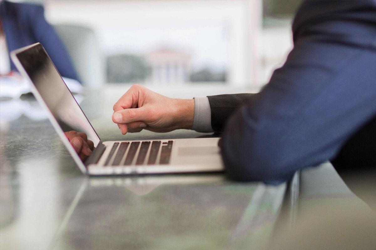 attorney's hands at a laptop keyboard, resting on a refletive table