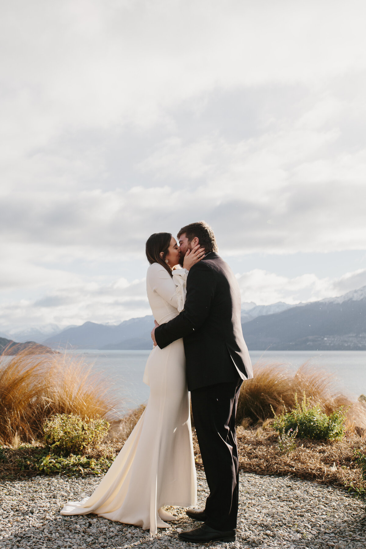 The Lovers Elopement Co - bride and groom kiss lakeside in Queenstown New Zealand