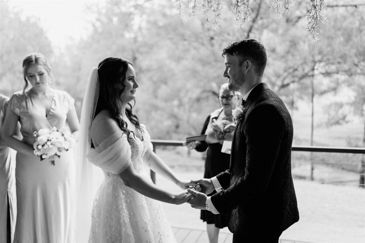 The bride and groom, standing beneath a canopy of flowers, exchange heartfelt vows as tears glisten in their eyes.