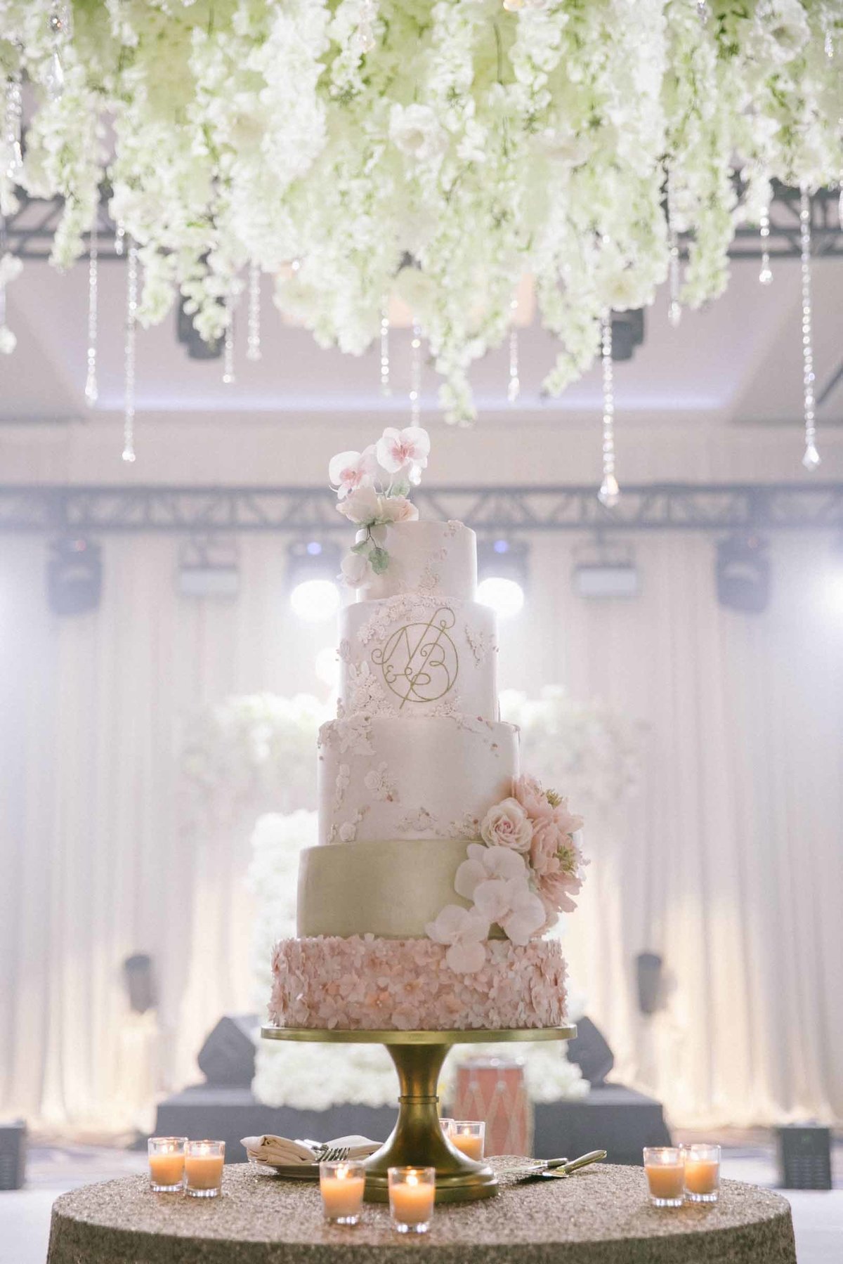 Beautiful pink and cream wedding cake underneath white floral instillation