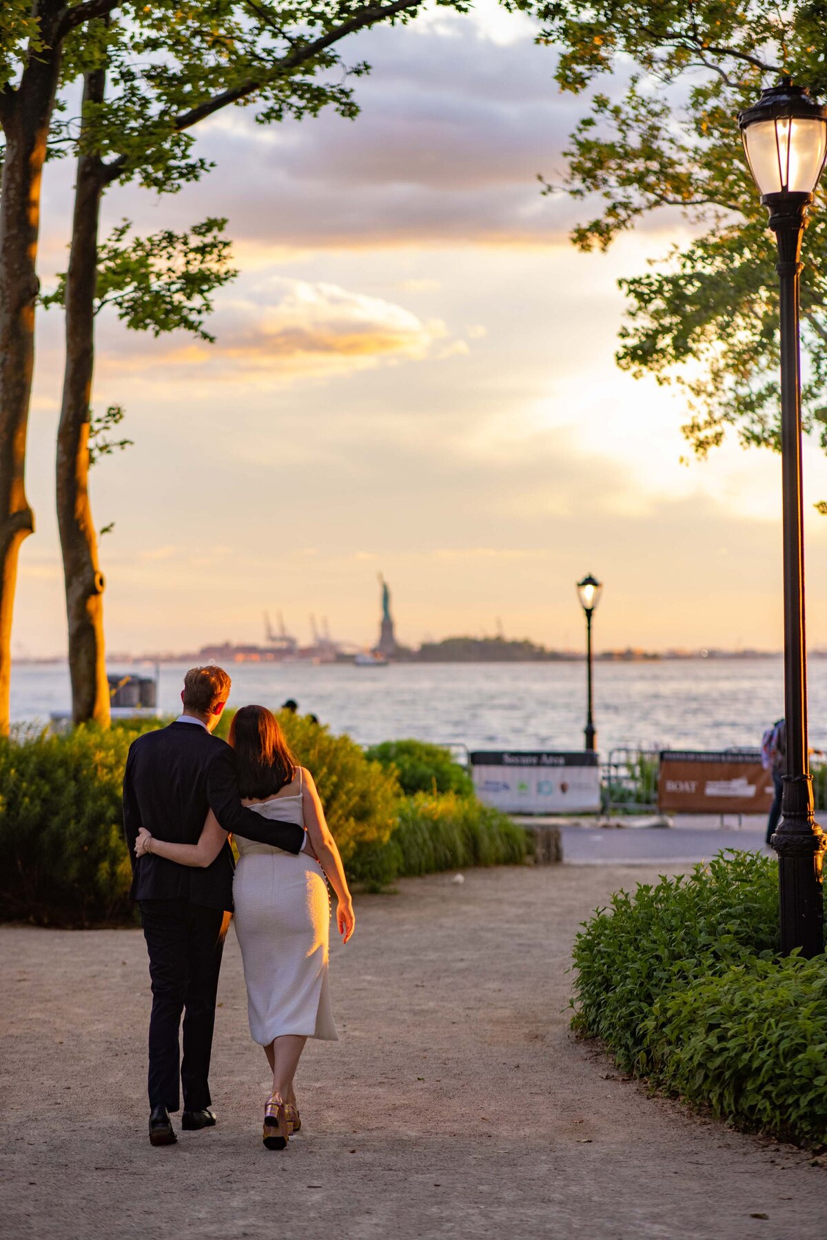 A couple walking along a path leading towards the water.