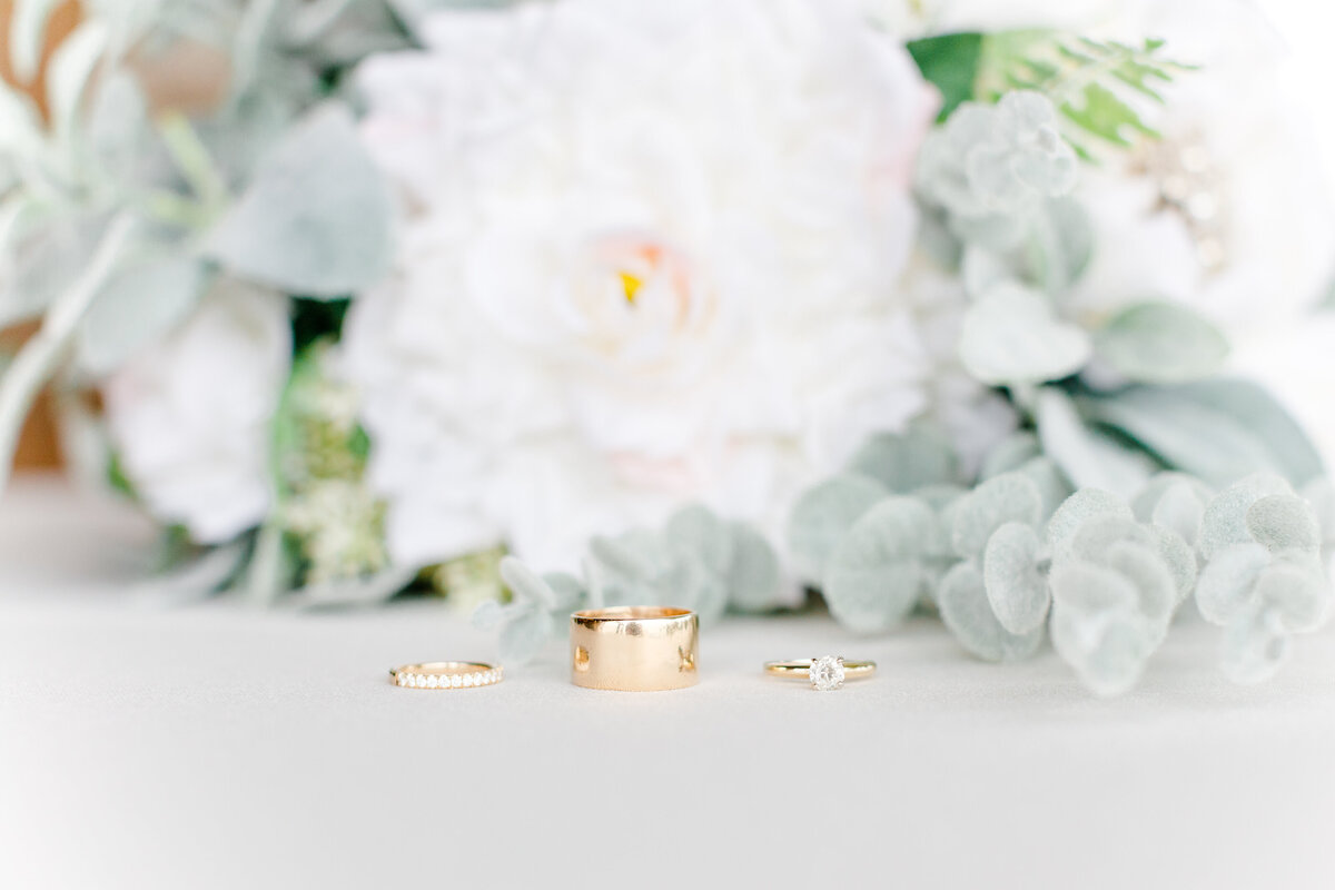 ring detail  with 3 lined up in rows  Grandfather's ring in center and white flowers behind