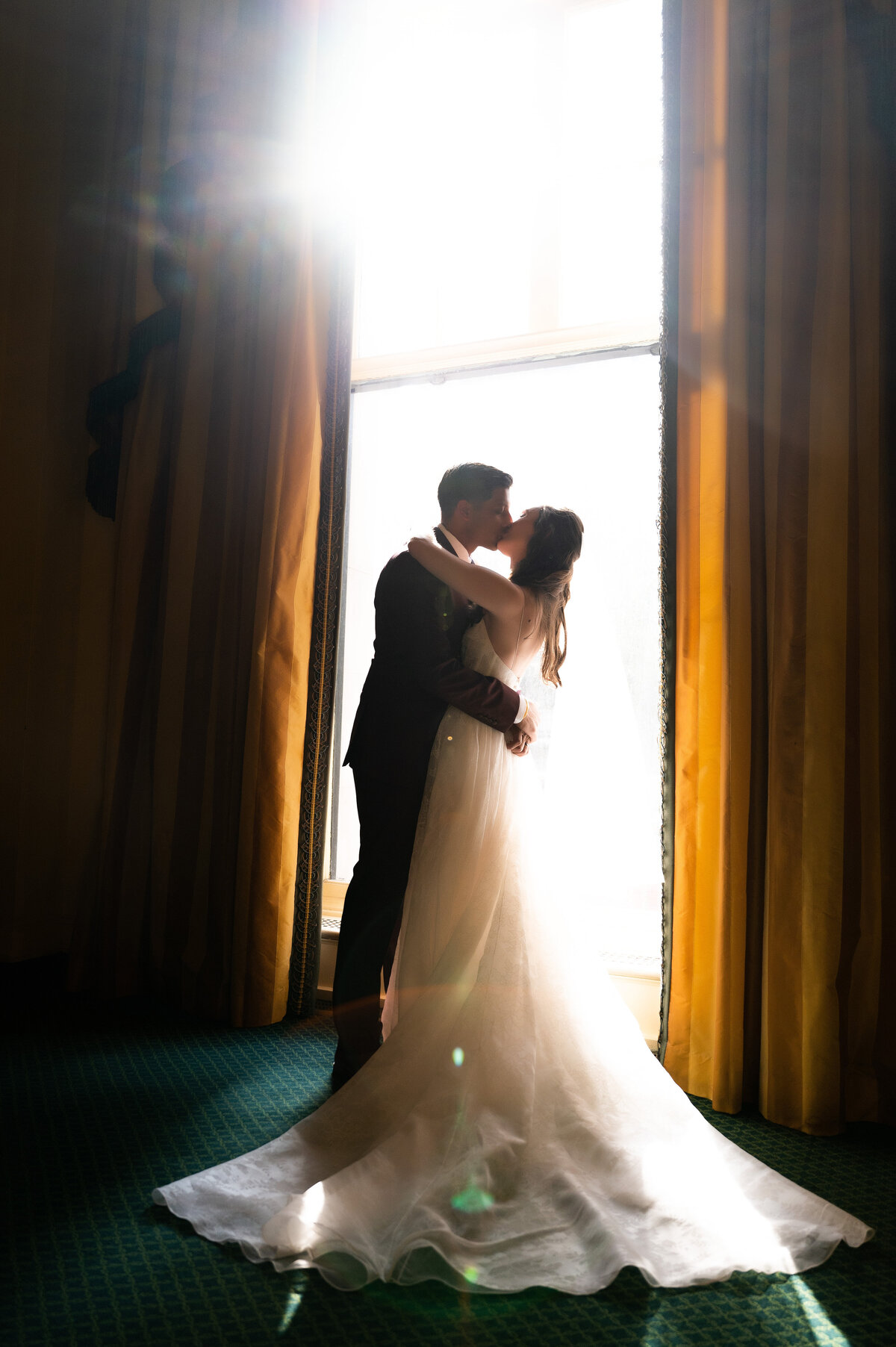 bride and groom kissing backlit window light