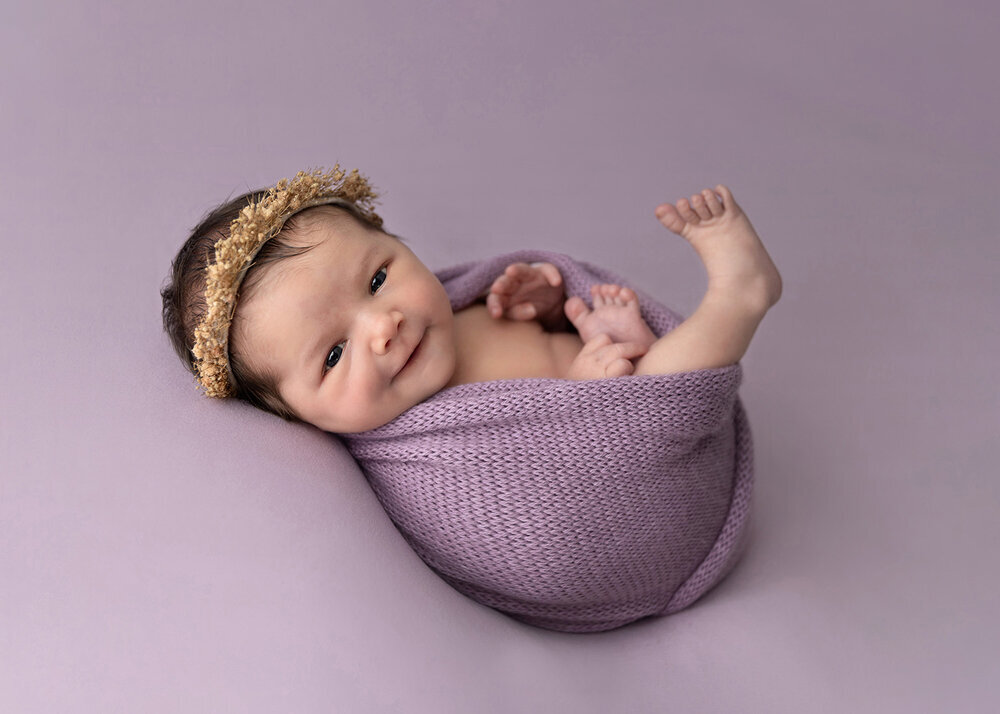 NEWBORN_BABYGIRLINPURPLELILACWRAPSMILING