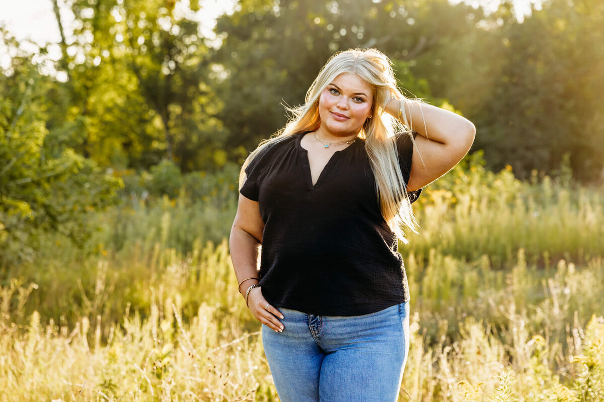 super pretty teen girl with blonde hair glimmering as she looks over at the camera during her senior photo session