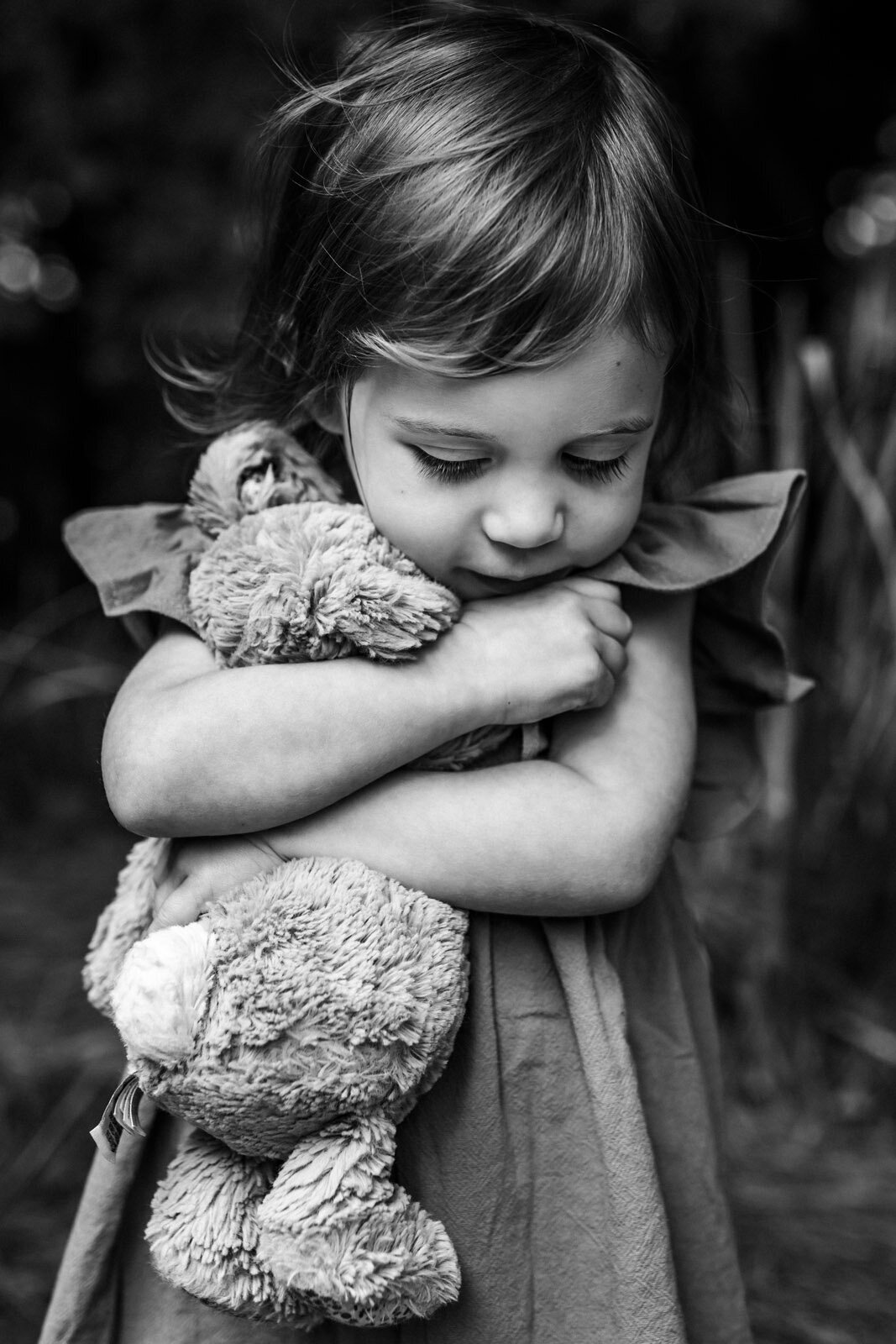 girl outdoors hugging her stuffed animal close