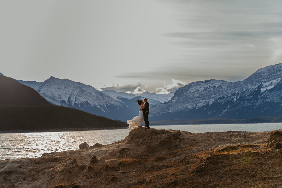 Bride and groom standing on top of hill during mountain destination wedding elopement