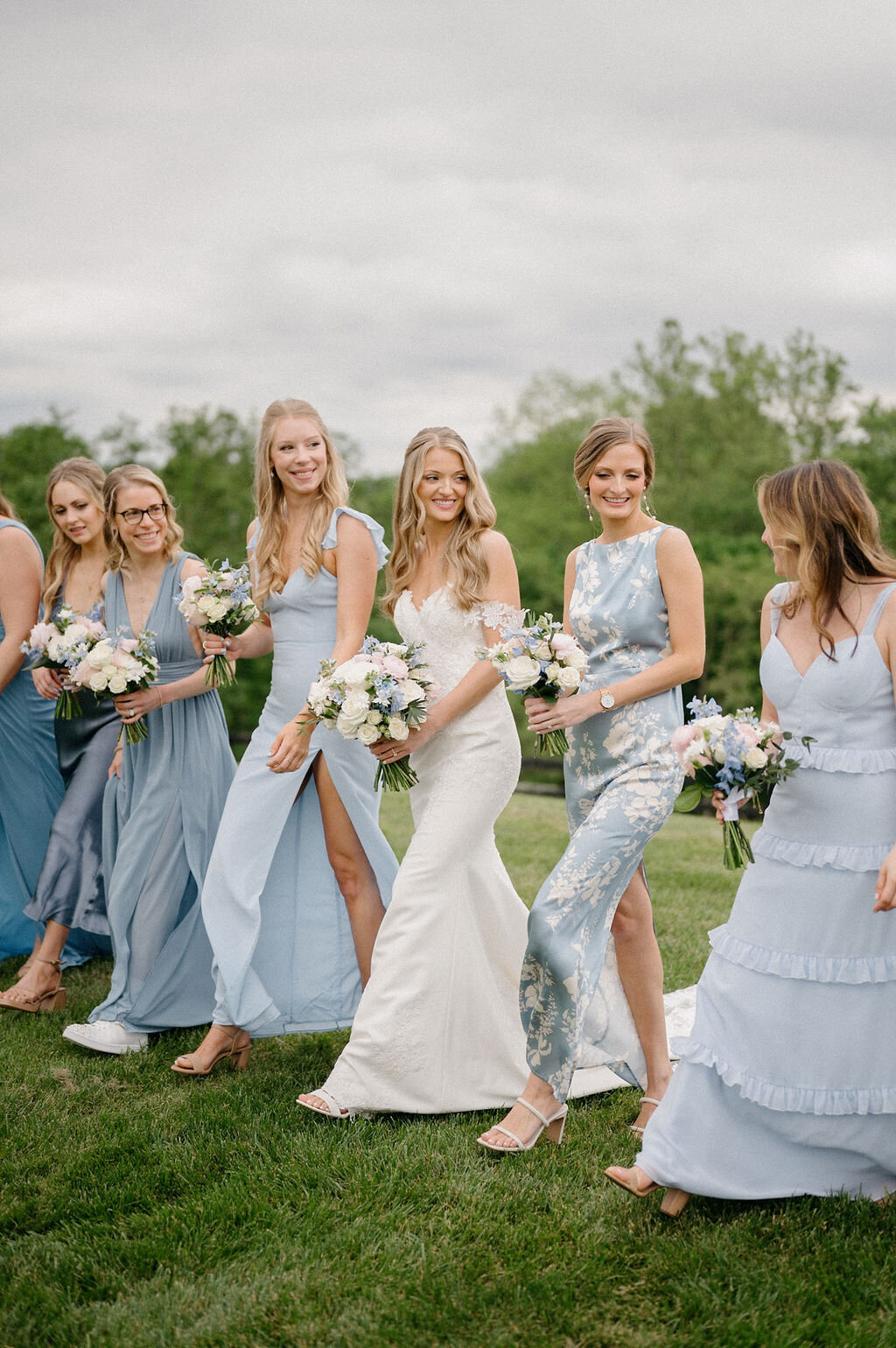Bride and bridesmaids walking outdoor while holding a bouquet