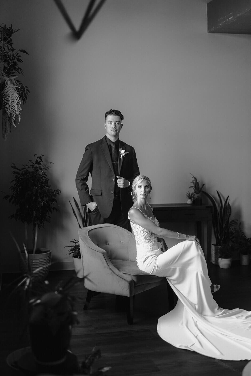Bride and groom portraits with groom standing and bride sitting down