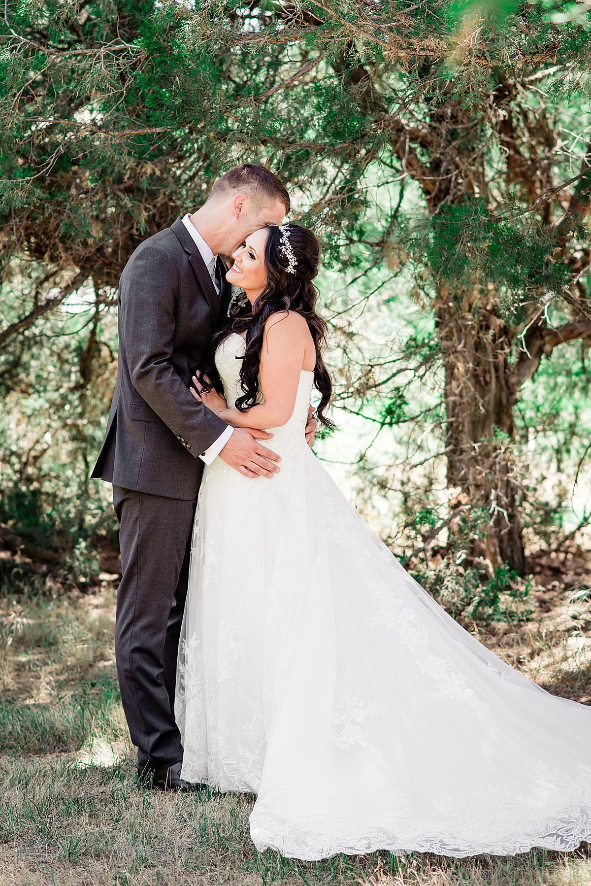 Portrait at Headwaters Ranch of couple on their wedding day, she is snuggled against him as he whispers in her ear