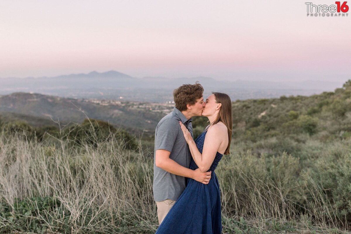 Engaged in a kiss overlooking  the canyon from atop of Top of the World