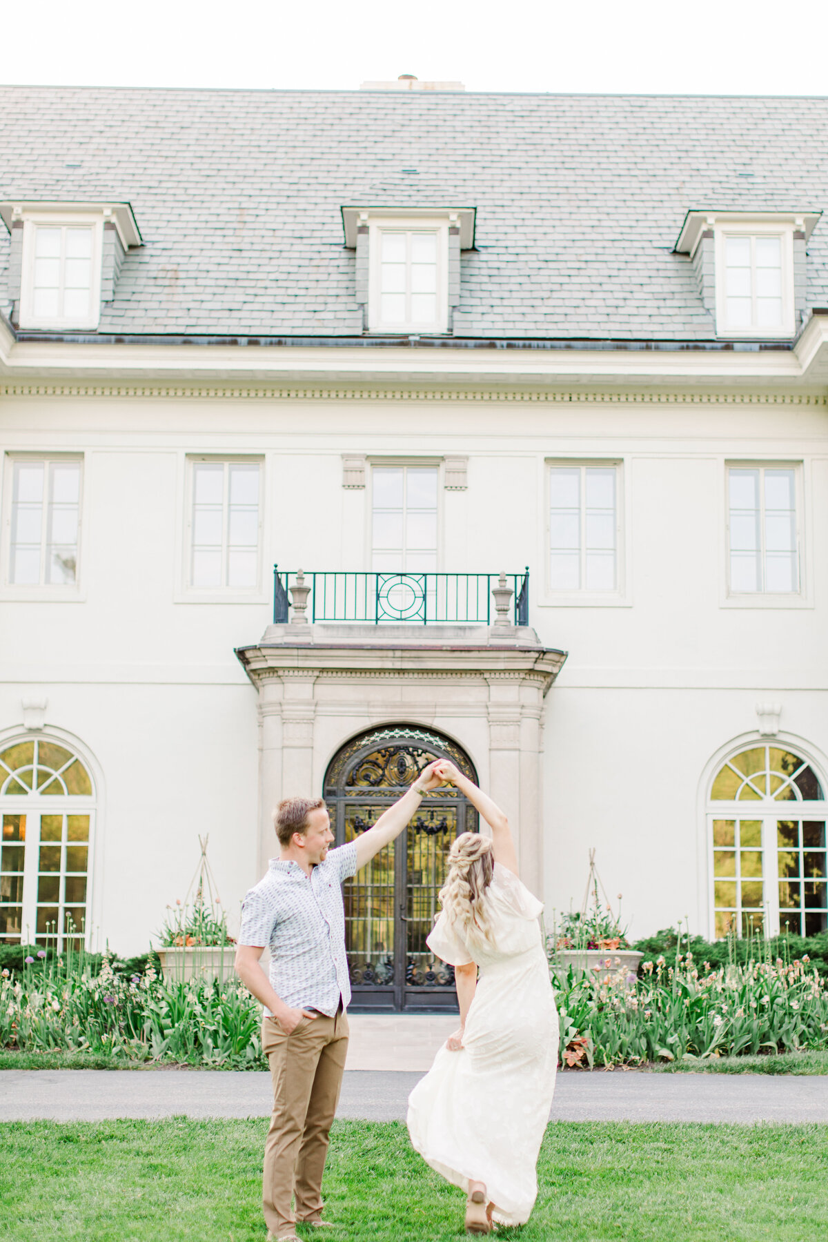 man twirling a woman in front of a building