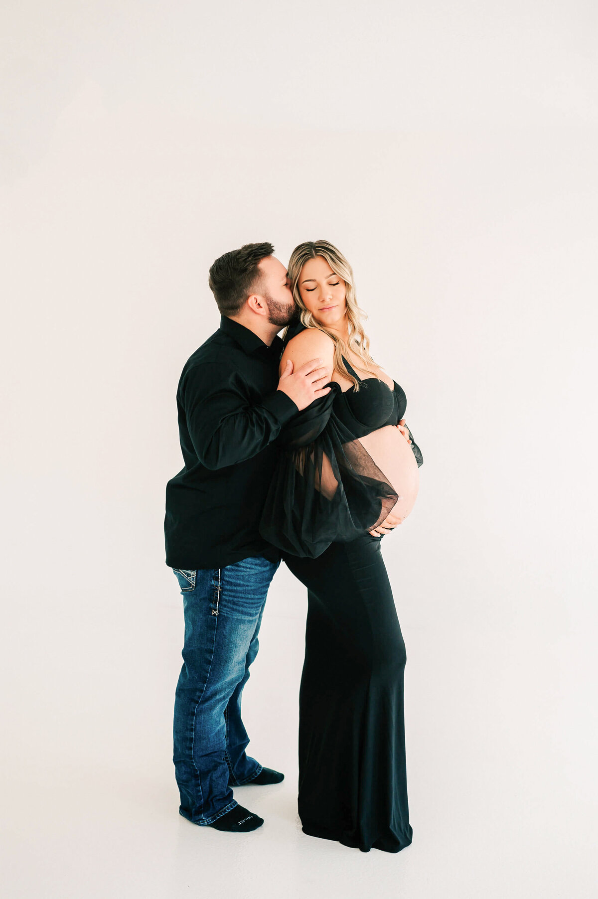 pregnant couple in black outfit cuddling enjoying their maternity photography in Springfield MO