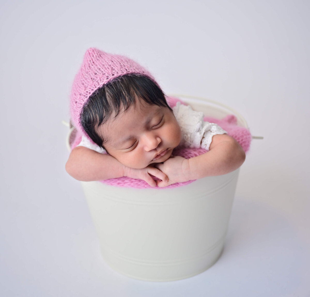 Newborn sleeping and posed in a white bucket.  Image by E. Benecki Photography.