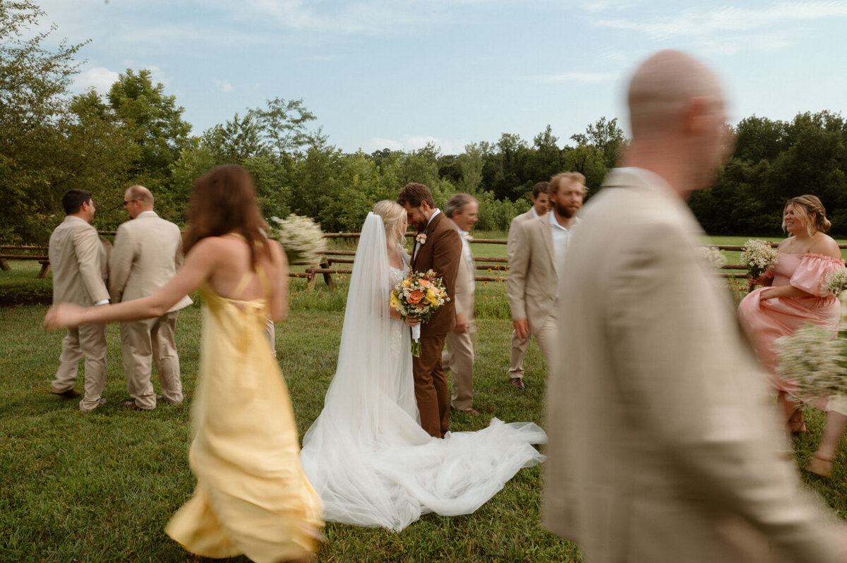 Wedding couple embracing as guests mingle around