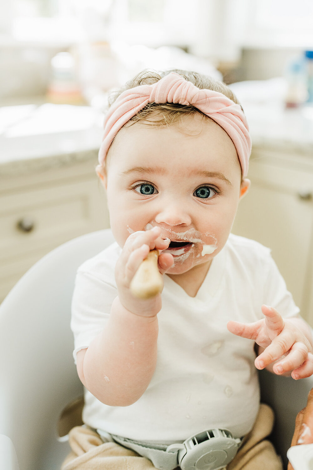 baby smiles at camera with yogurt on face