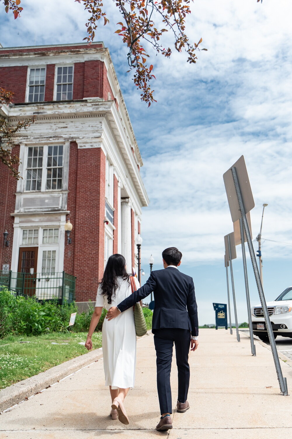 young couple walking up the steep sidewalk in front of the Somerville City Hall on the way to their civil ceremony