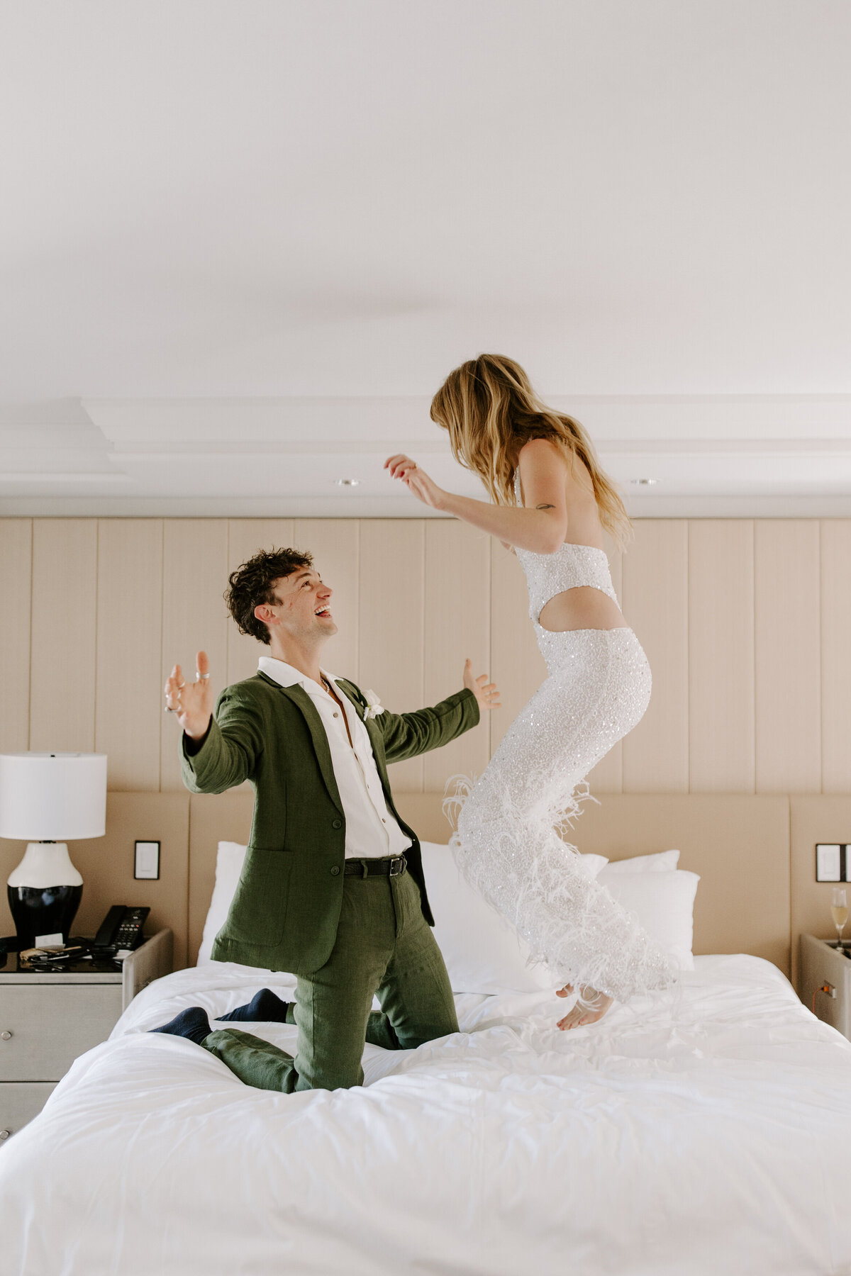 Partners jump around on a bed after their elopement.