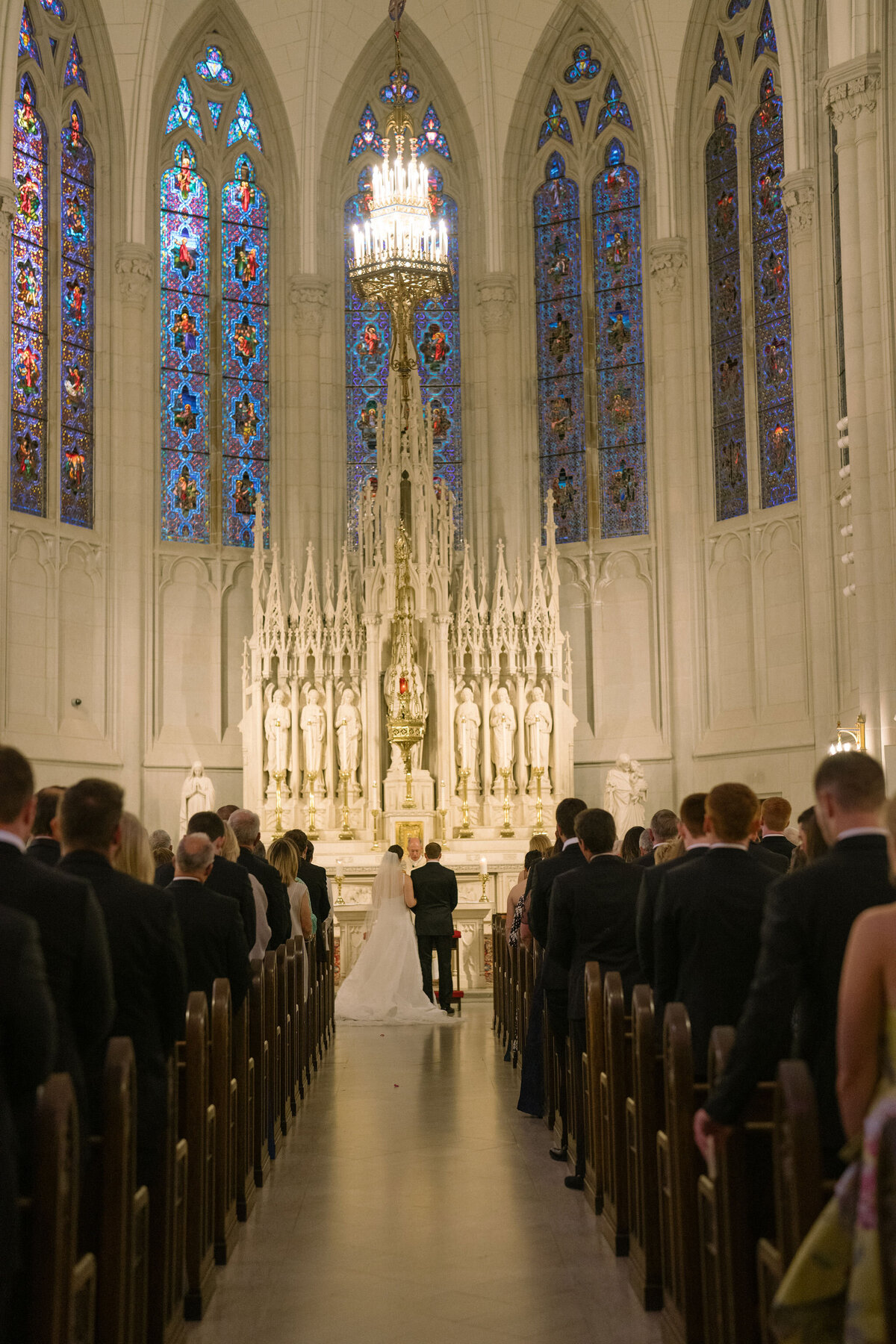 Guests witnessing the bride walking down the aisle in a magnificent church setting.