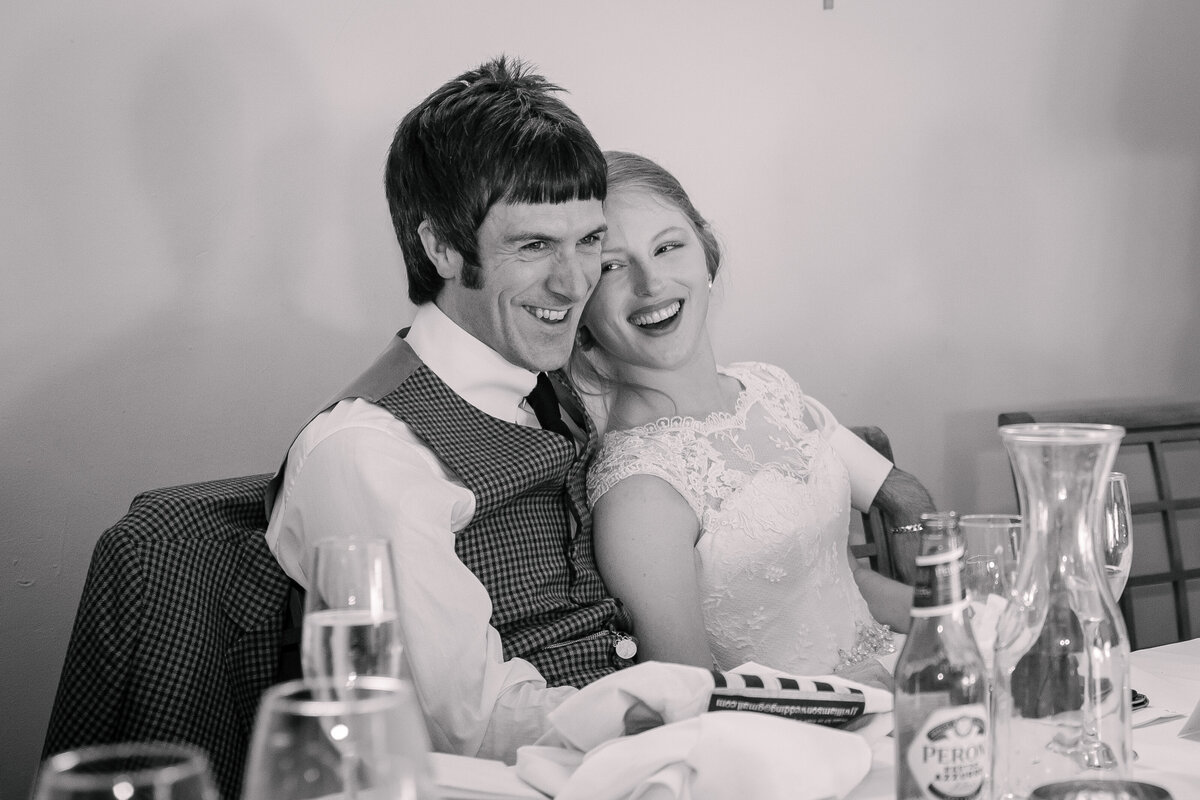 A bride and groom sitting at a table laughing