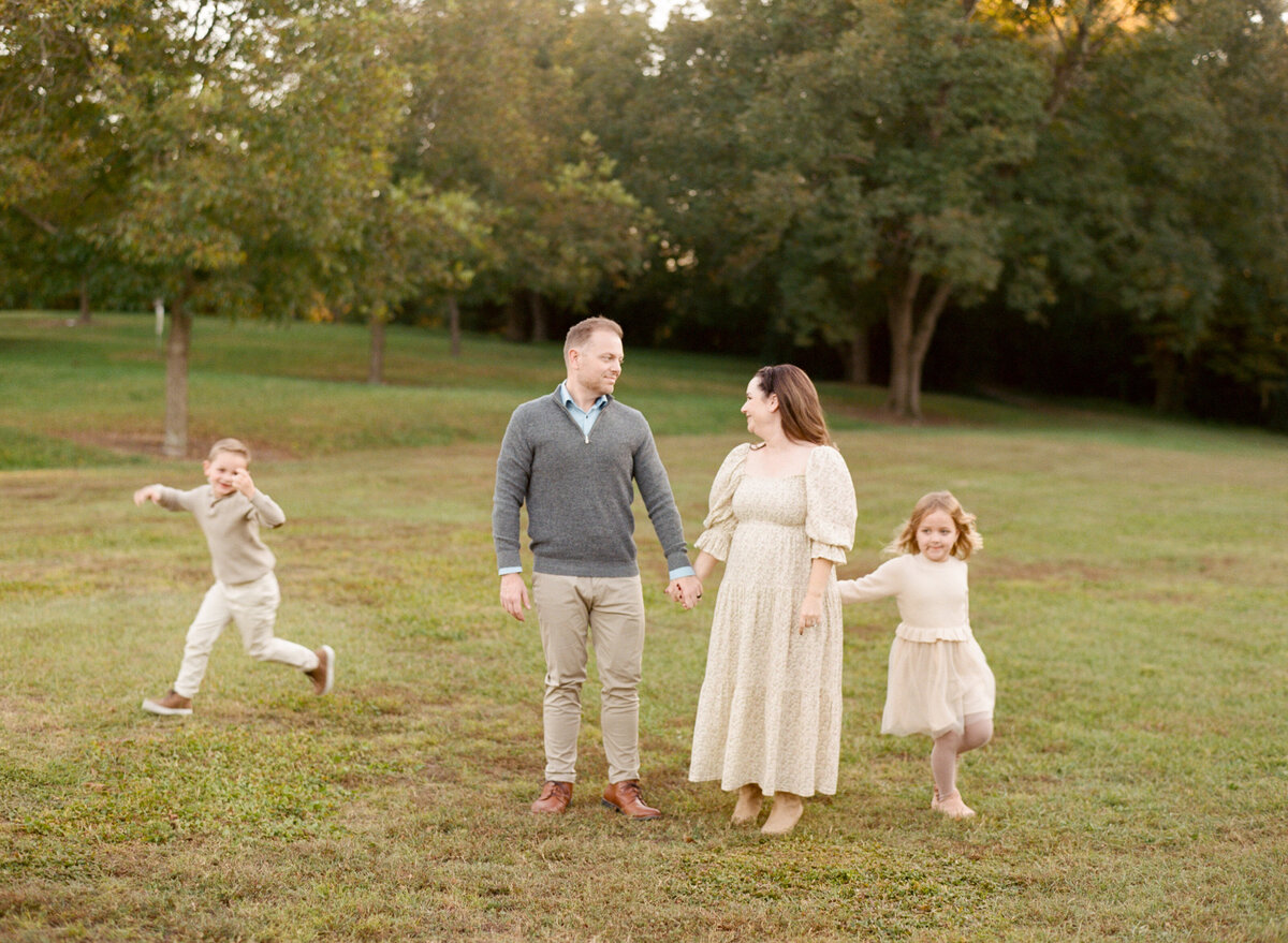 Family walks through the fields at Historic Oak View park in Raleigh for a maternity session. Image by Raleigh maternity photographer A.J. Dunlap Photography.