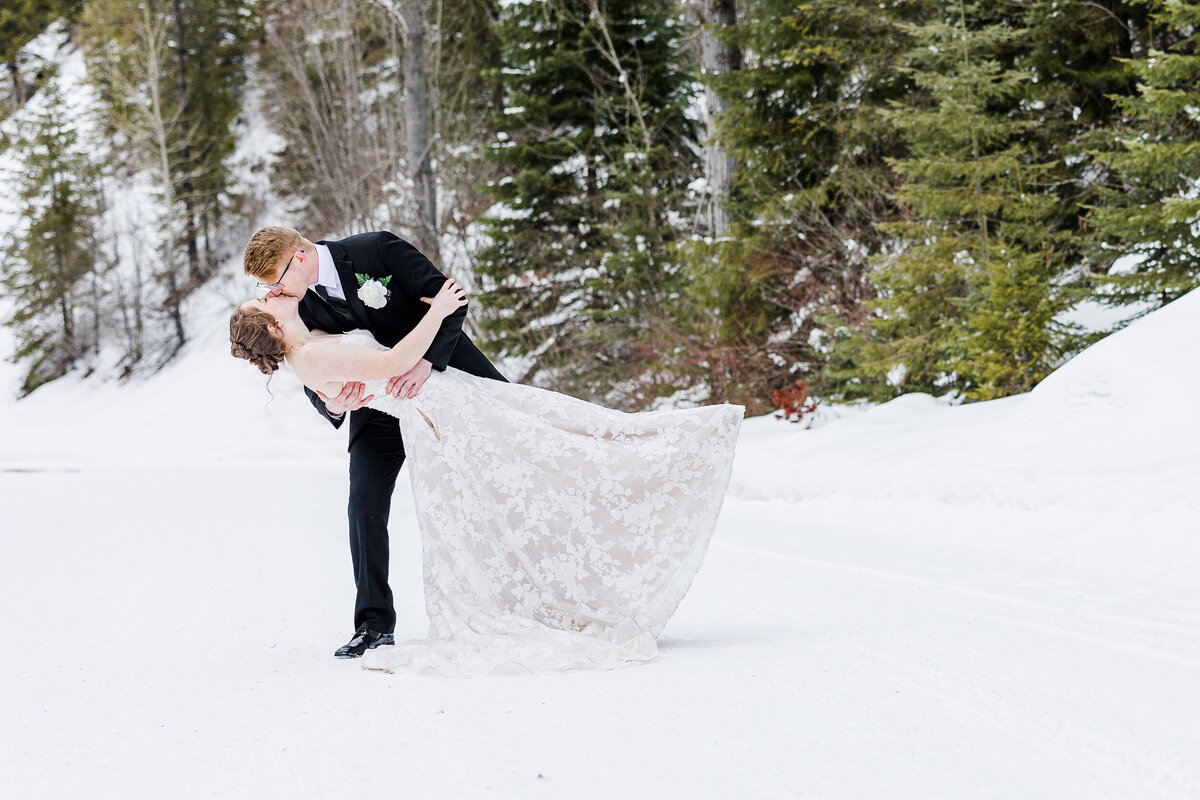 Winter Elopement in the forest Groom dipping Bride in a sweet kiss