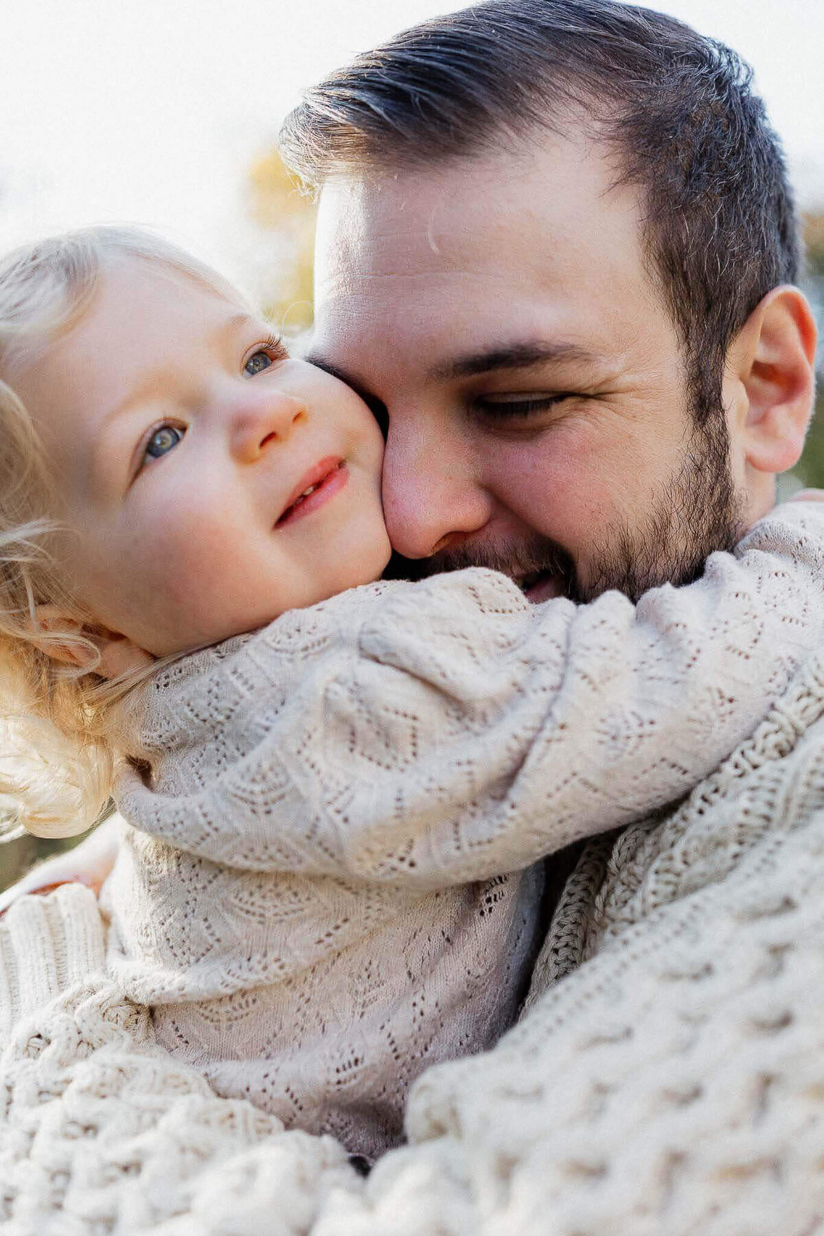 Close-up image of father hugging toddler daughter during fall family photo session at Cleveland Metropark.