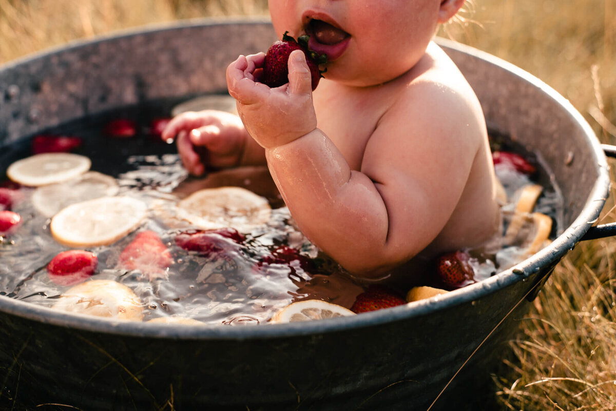 Baby eating strawberry in fruit bath family photos