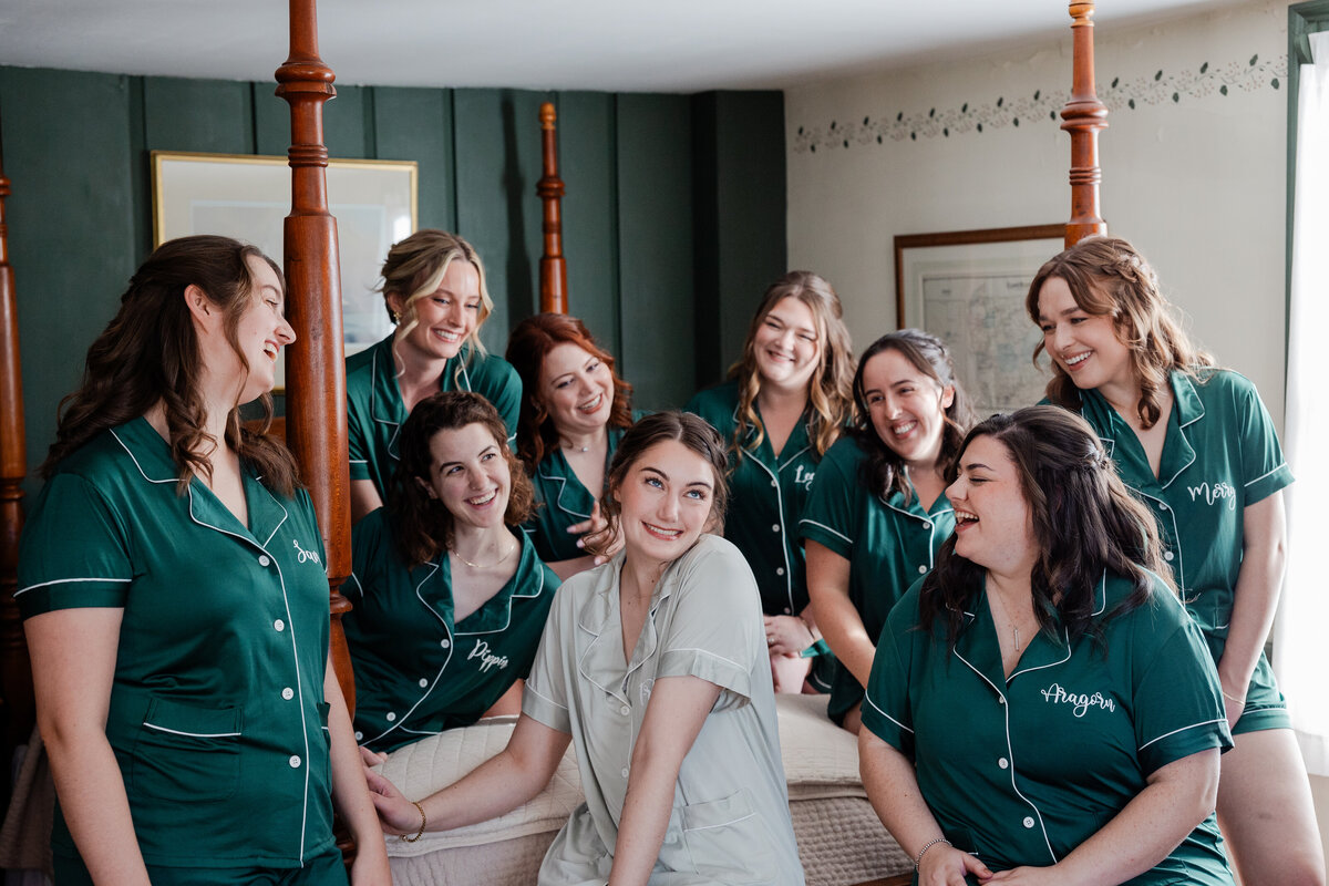 A Photograph of bridesmaids and bride on bed in pajamas.