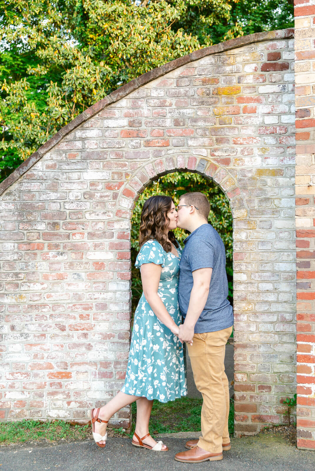 Couple kissing by brick arch at Chatham Manor in Fredericksburg, Virginia.