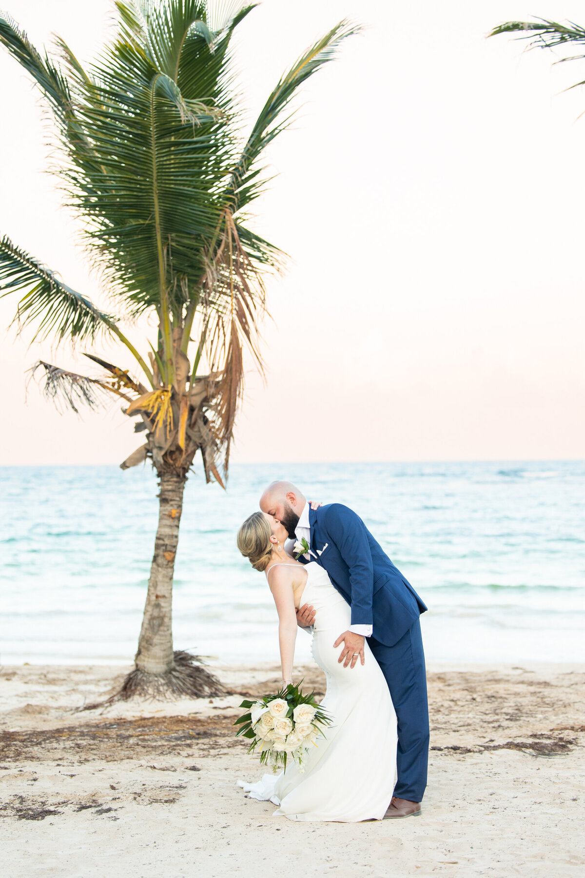 groom dipping his bride on the beach