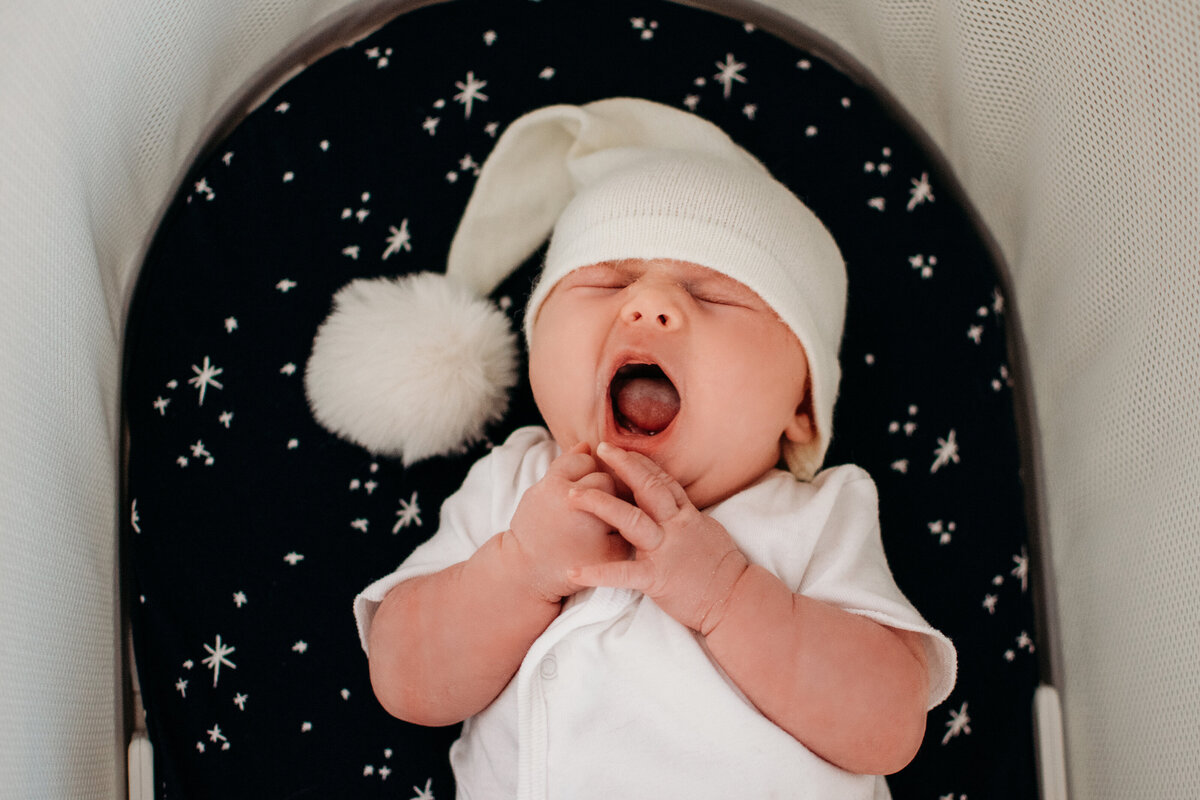 new baby girl yawns in her snoo bassinet during a lifestyle newborn photoshoot in Chicago, IL