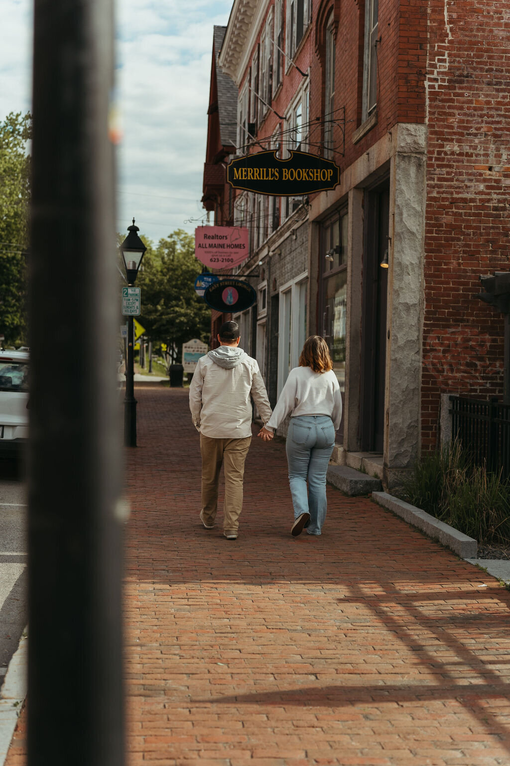 Photo of couple holding hands walking together downtown Central Maine