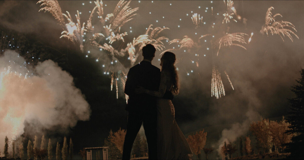 Couple watching fireworks during their wedding reception, captured by Prairie Orchid Weddings, wedding videographers in Lethbridge, Alberta. Featured on the Bronte Bride Vendor Guide.