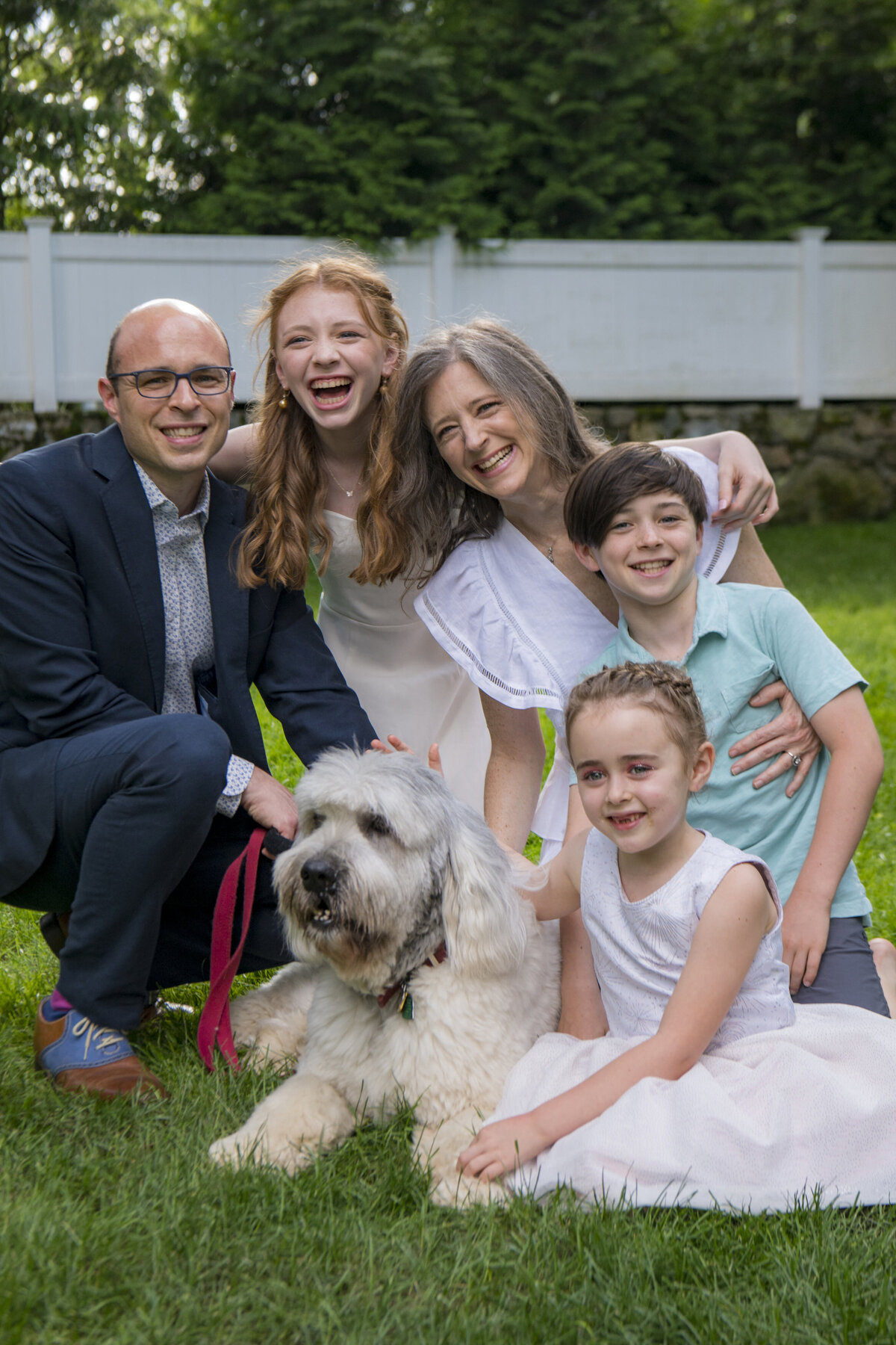 A family smiling together with their dog laying in front of them 