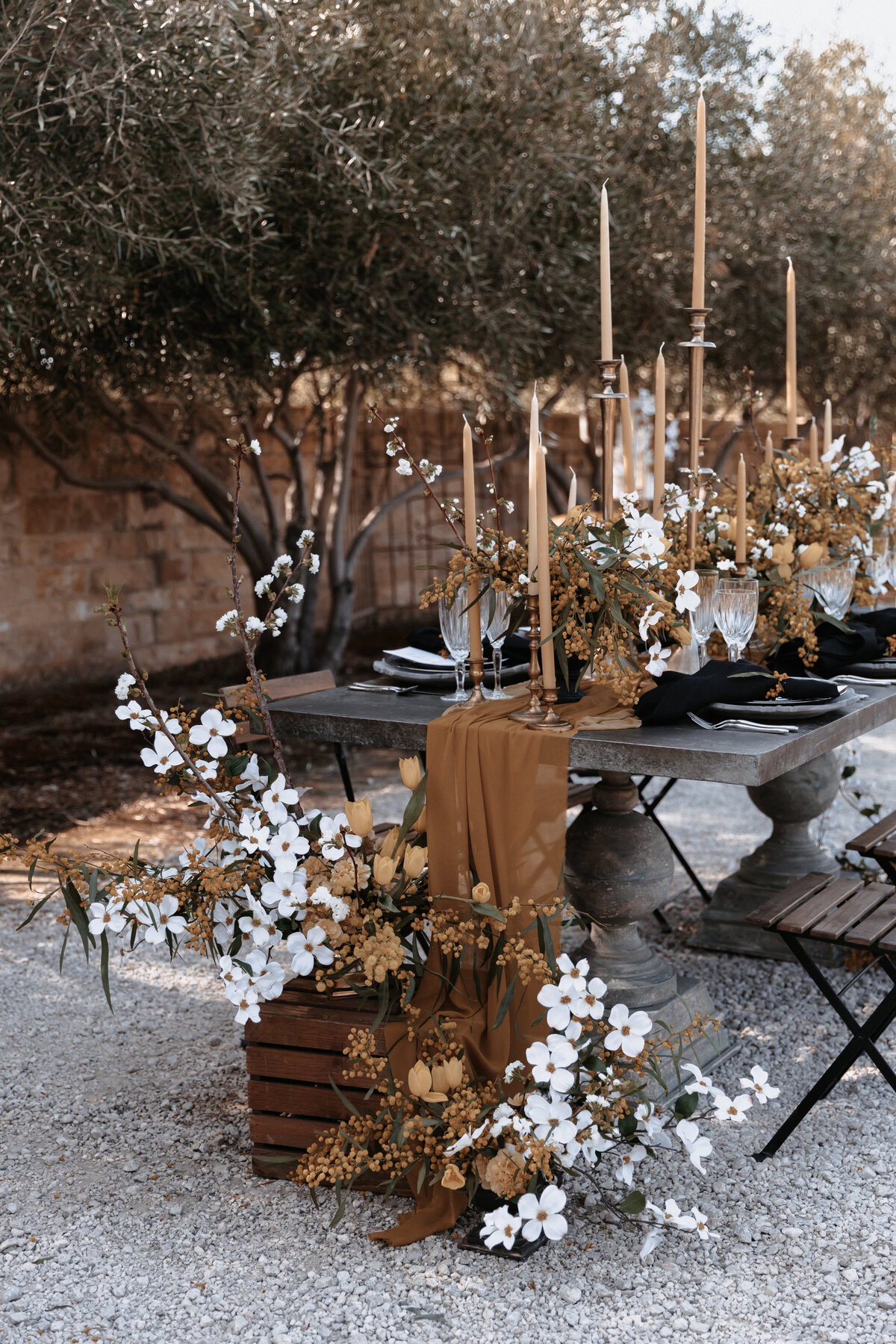 Elegant wedding reception table with white and gold florals, gold candlesticks, and black table settings at Sunstone Winery.