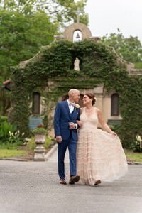 Newlywed couple walking arm-in-arm past ivy-covered historic stone chapel during St Augustine elopement photography session