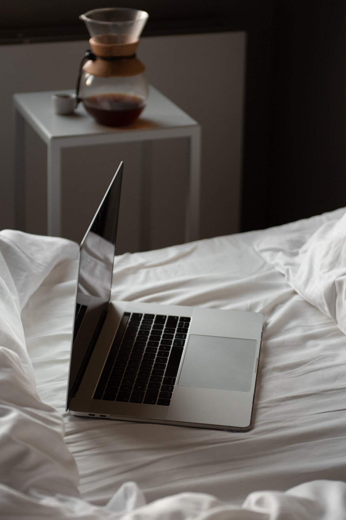 moody editorial photograph of a laptop in bed