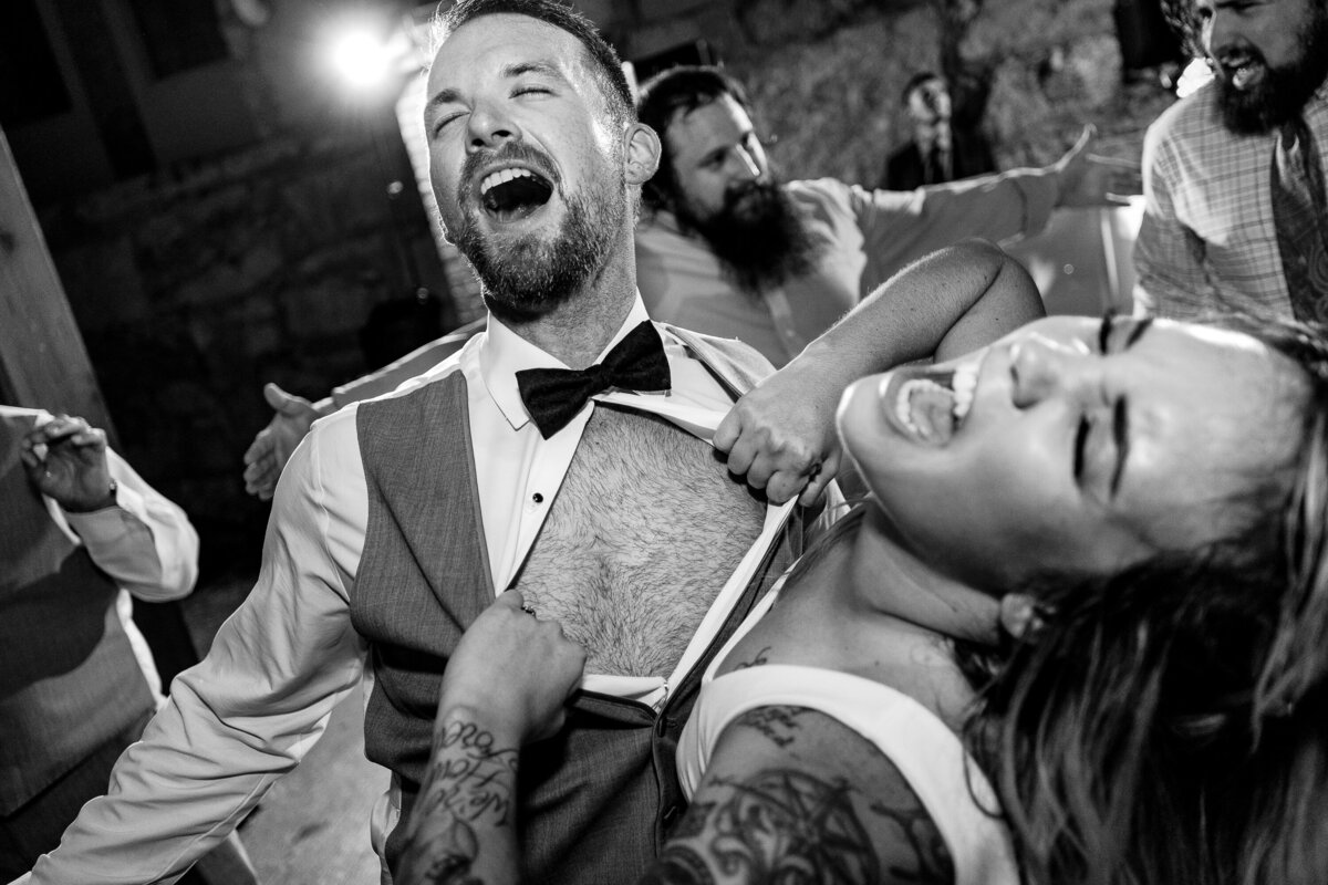 A bride rips open her groom's shirt on the dance floor during their wedding reception at  Chateau Rive in Spokane, Washington.