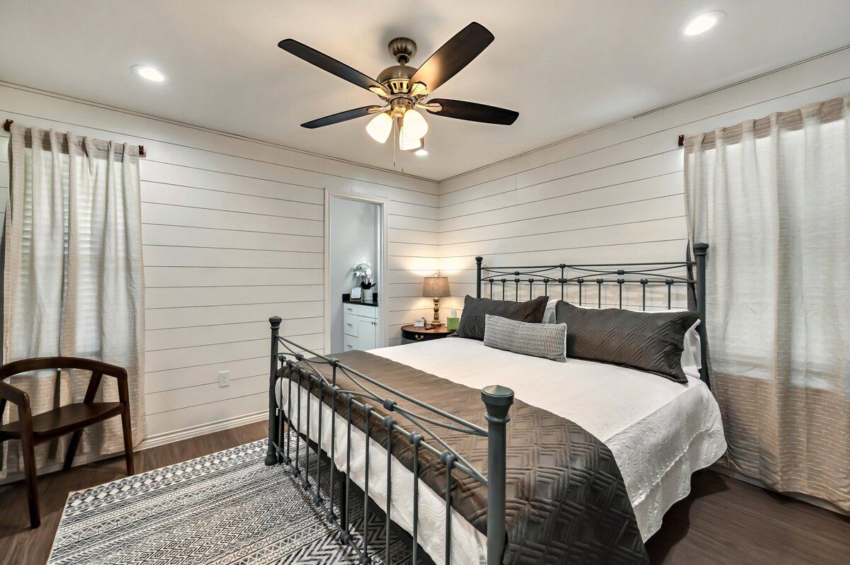 Bedroom with beautiful bedding in this four-bedroom, 4.5 bathroom new construction vacation rental house with free wifi, fire pit, gazebo, cornhole, private bathrooms for each bedroom within walking distance of Magnolia and Baylor in downtown Waco, TX.