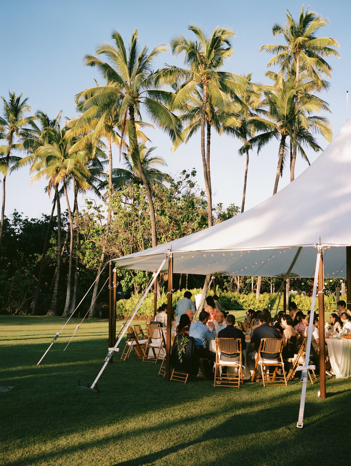 Elegant marquee dinner setup at sunset during a wedding at Lanikuhonua Cultural Institute — by Kate Winters Photography.