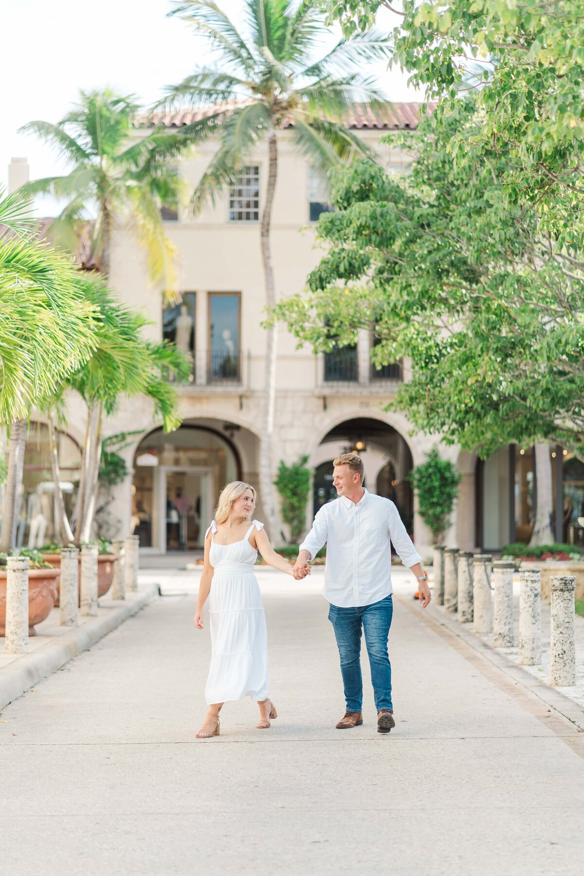 a couple holding hands walking while looking at each other and smiling