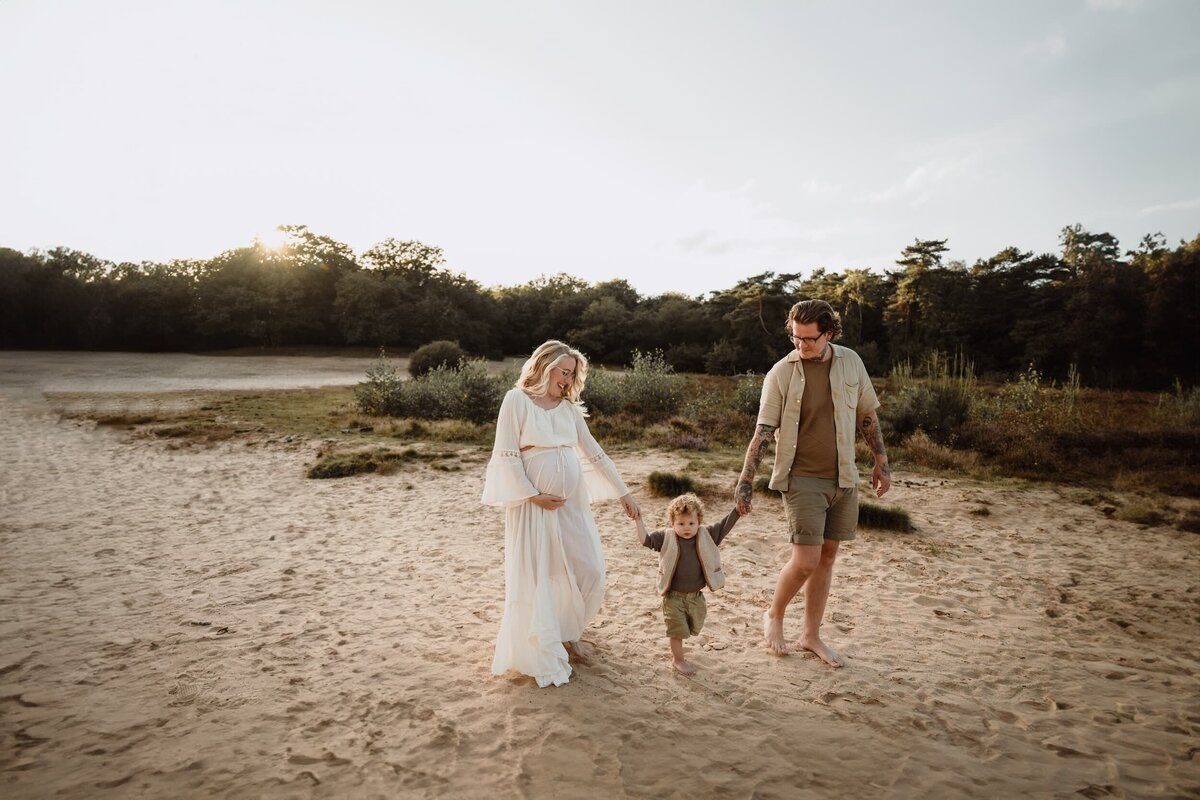 zwangere dame met gezin tijdens golden hour in duinen