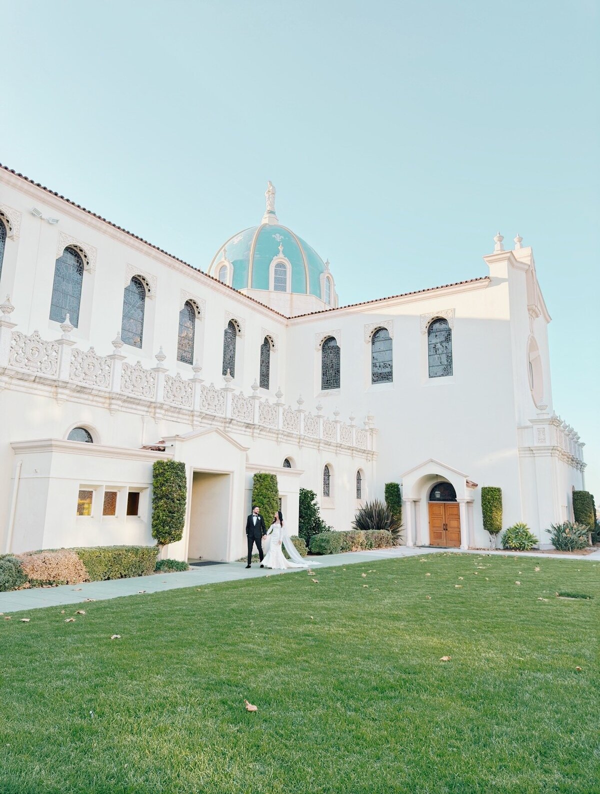 Bride and groom walking outside The Immaculata Catholic Church during their portraits.