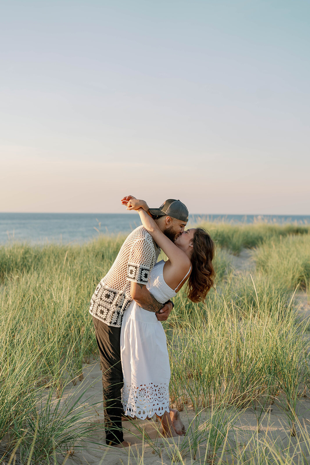 Lake Michigan sunset engagement picture of couple kissing in the dunes at New Buffalo Beach