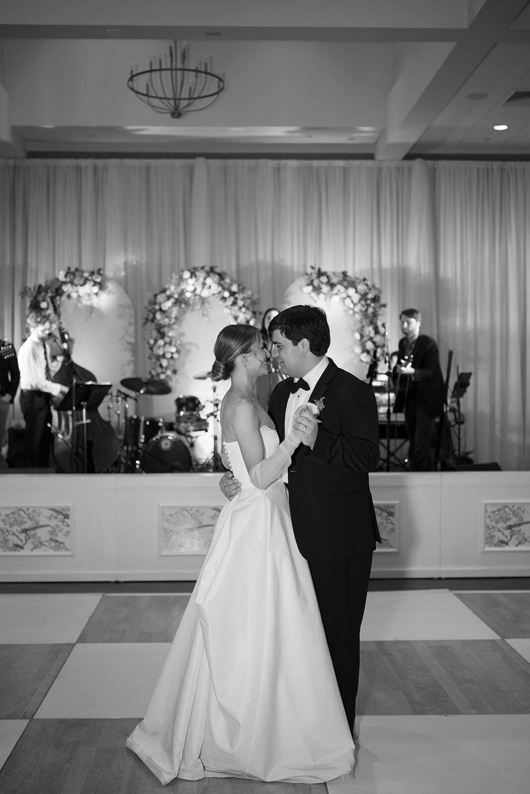 Bride and groom sharing their first dance at their Burritt on the Mountain wedding reception, holding each other closely on the dance floor as the live band performs in the background.