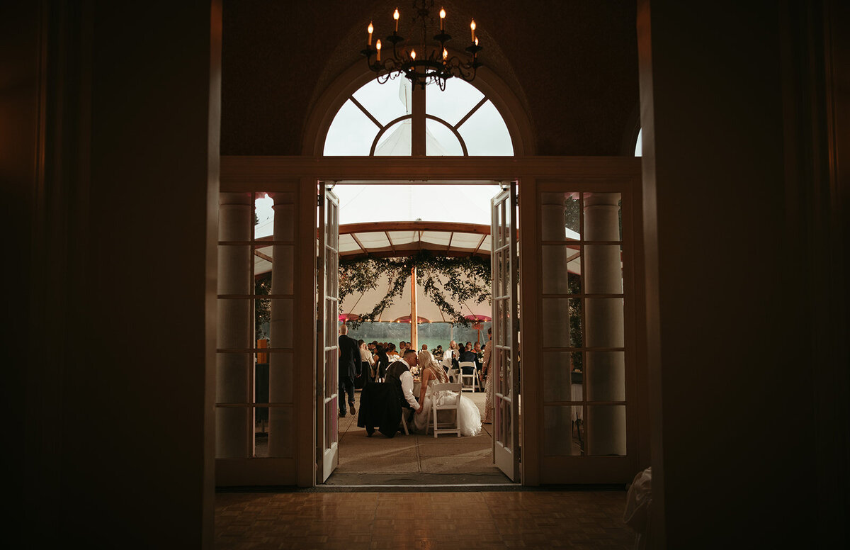 couple lean in to kiss at their sweetheart table at wadsworth mansion wedding photo by cait fletcher photography
